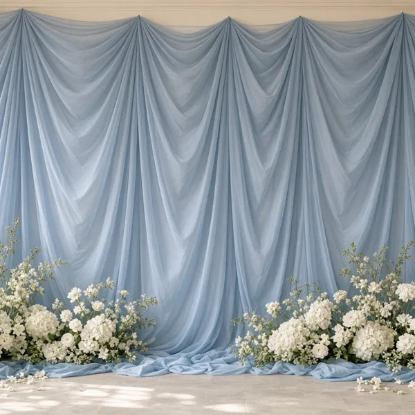 Dusty blue chiffon backdrop drapes styled for a wedding table